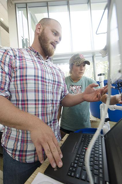 Chris Dunham, nutrition and sustainability specialist for NC State Dining, and Madeleine Ciszewski, a junior studying agriculture science and president of the Recirculating Farms Club, adjust some wiring as a part of the aquaponics exhibit in Talley Student Union on June 29. This aquaponics exhibit was sponsored and put on by the Recirculating Farms Club. The Recirculating Farms Club has applied to take its exhibit to the North Carolina State Fair.