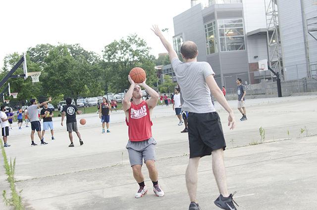 John Willis, alumnus, shoots a jump shot as Mike Simon, alumnus, attempts to block his shot on June 29 on the outdoor basketball courts of Carmichael Gym. The Carmichael outdoor basketball courts are four of the gym&#8217;s 15 basketball courts. Alumnus Kevin Martel joined Willis and Simon for the game.