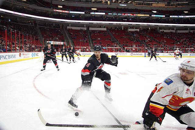Carolina Hurricanes left wing Phillip Di Giuseppe battles Calgary defender Kris Russell for the puck against the boards. The Hurricanes defeated the Calgary Flames, 5-2, at PNC Arena on Jan 24.