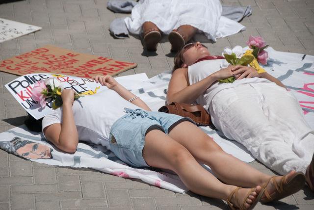 Protesters stage a "die-in" by lying down for several minutes on the hot bricks in front of the Administration Building. The demonstration paid respect by representing the losses from police killings.