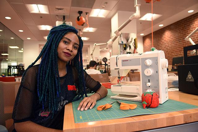 NC State alumna Jazsalyn McNeil sits alongside sewing materials provided by D.H. Hill Library's Makerspace. McNeil was part of a team that created a dress equipped with circuitry and lighting. The dress, named "Pulse," was featured in Charleston Fashion Week's 10th anniversary show and on a TEDx talk highlighting technology in textiles.&#160;