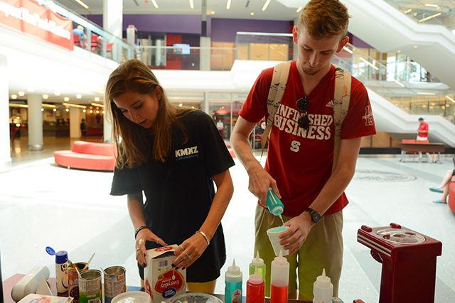 Amy Hinds, a sophomore studying biology, gets a spoon out of a box. Stephen Sawyer, a junior studying nuclear engineering squirts raspberry flavoring for a snow cone in the lobby of Talley Student Union on Thursday. Hinds, as well as other members of Fusion Dance Crew, held a fundraiser in which they sold snow cones and specialty desserts such as bao-bing and patbingsoo. "Fusion is a family that works really hard and dances together for fun," said Nicole Seah, a senior studying business administration and the social chair of the organization.
