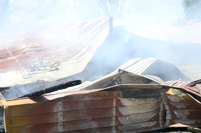 Pieces of tin roof from a poultry compost barn lie twisted and smolder over ashes of compost on Aug. 15. The tin will have to be moved later so workers can apply water to the compost and completely extinguish the fire.