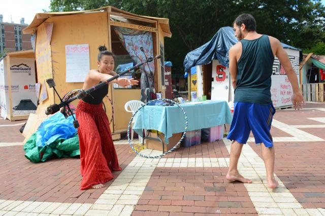 Phian Tran, a senior studying agriculture business management, tries to perform a barrel roll with a dragon staff as Gio Camacho, a flow artist with Cirque du Vol watches at the Brickyard on the last day of Shack-a-Thon Friday. The Good Club's shack called the "Goodzebo" had guest performing artists throughout the week to come out to promote both Cirque du Vol and Celestine Movement Arts. According to club officer and freshman studying social work Sara Darwish, the Good Club is about spreading happiness and wellness around campus.