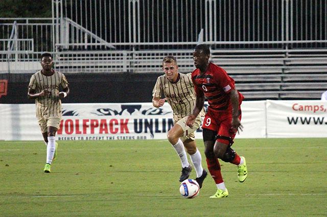 Sophomore forward Ade Taiwo runs the ball, keeping it away from College of Charleston's Lorenz Esposito at Dail Soccer Stadium Aug. 31, 2015. The Wolfpack defeated the Cougars 2-0, with one goal by freshman forward Julius Duchscherer, and another by junior midfielder Yanni Hachem.