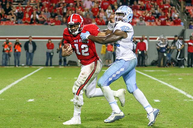 Redshirt senior quarterback Jacoby Brissett stiffarms a UNC defender during a 31 yard run in the second half. Brissett finished with 17 for 37 passes completed and 207 yards with 2 touchdowns and one interception. Brissett also had 20 rushes for 128 yards and 2 touchdowns. The NC State Wolfpack fell to the UNC Tarheels, in the last home game of the season, 45-34 at Carter-Finley Stadium on November 28, 2015.