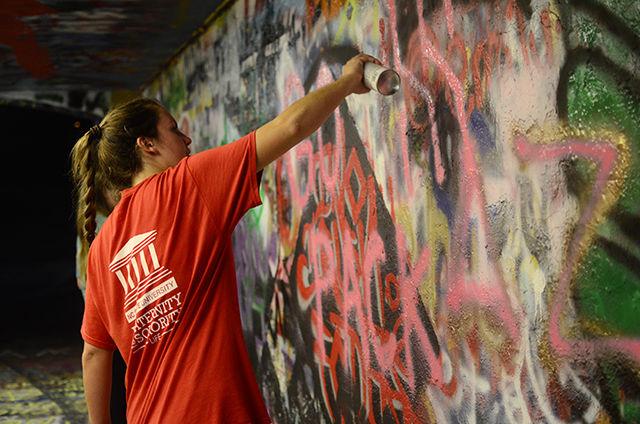 Monica Driscoll, a junior studying biochemistry&#160;and member of the Panhellenic sorority Delta Zeta, paints the Free Expression Tunnel with the words "Go Pack Delta Zeta" on Aug. 18. Driscoll and three of her sorority sisters also began painting a section of the free expression tunnel with the message "Delta Zeta wants you to go Greek.&#8221; Rush for Fraternity and Sorority Life begins this Friday and will end Wednesday. "We are promoting and supporting recruitment for Greek Life as whole," Driscoll said.