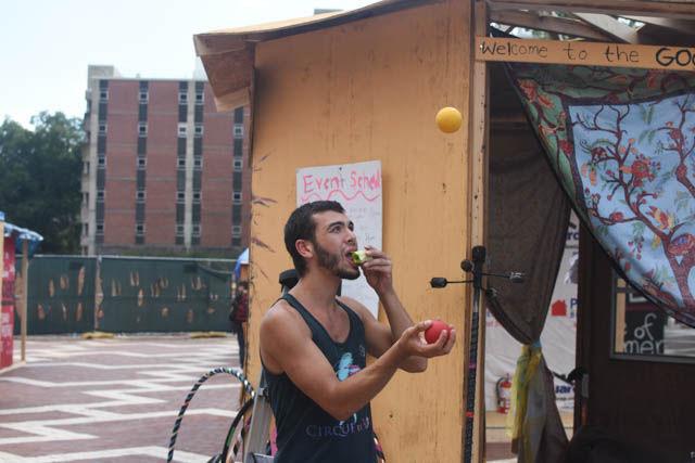Gio Camacho, a performer of Cirque de Vol, juggles balls into the air while eating an apple at Shack-a-Thon in the Brickyard on Friday