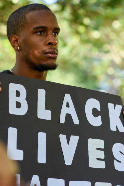 Wesley Coats, senior studying computer science and president of the Kappa Lambda chapter of Omega Psi Phi fraternity, holds a sign that reads "Black Lives Matter" during the NC State Blackout event. Students gathered in Wolf Plaza on Friday to listen to speakers and bring awareness to the recent events that took place in both Charlotte and Tulsa. "There comes a time when silence is inexcusable. We can't ignore the violence and oppression that's happening among our people," said Coats.