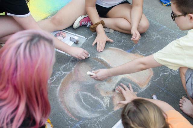 Millbrook High School seniors paint a picture of Frida Kahlo at this year&#8217;s SPARKcon on Fayetteville Street in downtown Raleigh on Sept. 16. Artists are allowed to create teams to work on their square or set of squares for the street painting category.