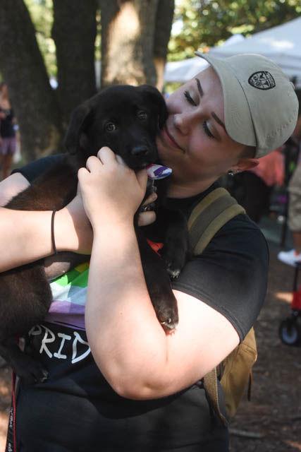 Julz South, a student at Millbrook High School, holds a puppy up for adoption at the Pride Parade event at Duke University on Saturday. The shelter brought many animals in need of adoption.