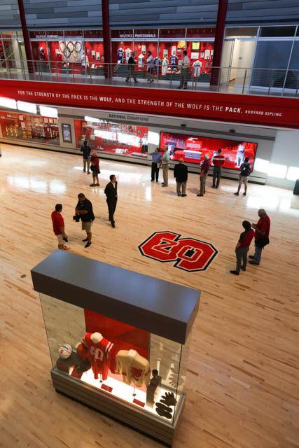 Media hover around the interactive display inside of the grand hall museum of Reynolds Coliseum on Sept. 7. Reynolds has completed its renovation, shrinking its seating capacity and adding a new museum portion. Memorabilia can be found all around the venue, including Reynolds and NC State history at the south entrance, a walk of fame and display cases for each of the current varsity sports ringing the seating area and the grand hall.&#160;