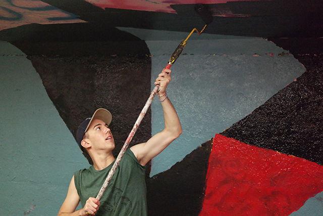 Gray Hancock, a first year student studying animation, paints the Free Expression Tunnel early Friday morning during an activity put on by the Design Council. Students from the College of Design started working to paint the tunnel in its entirety on Thursday night, and finished early in the morning on Friday. Hancock and other students participating said that they liked the fact that the activity allowed them to give the tunnel a "fresh start" every year, and that painting the tunnel was a good way to build community among students in the College of Design.&#160;