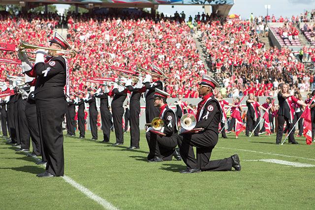 Lorenzo Melton, a junior studying technical, engineering and design education and Parker Gagnier, a sophomore studying philosophy and ethics, kneel during the playing of the national anthem before the game against Wake Forest on Saturday in Carter-Finley Stadium. Kneeling was done as a form of protest, along with the blackout, where a section of students wore all black and raised their fists protesting the racial prejudice against African-Americans by the police.