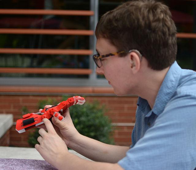 Elliot Krause, a junior studying biomedical engineering at UNC-Chapel Hill and the president of Helping Hands, shows off a prosthetic device made by the Helping Hands club at UNC-CH. Helping Hands is non-profit organization based at UNC-CH that makes prosthetic devices for children at no cost to families. The parts of the prosthetic are 3D printed and assembled with other materials such as string and elastic that allow them to move.