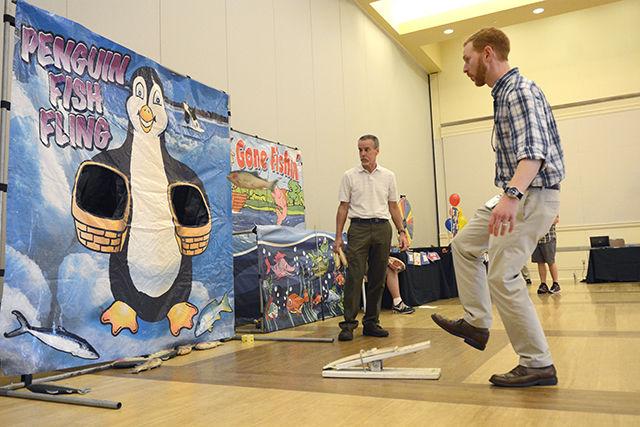 Bill Coker, manager of software licensing with the Office of Information Technology, watches as Dana Di Maio, office manager with the Office of Scholarships &amp; Financial aid, launches a fish while playing a game at the &#8220;Make it Your Mission to Stop Phishing Fair.&#8221;