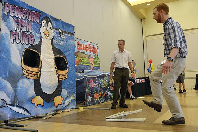 Bill Coker, Manager of Software Licensing with the Office of Information Technology, watches as Dana Di Maio, Office Manager in Scholarships &amp; Financial Aid, launches a fish into a target in a game called Penguin Fish Fling at the Make it Your Mission to Stop Phishing Fair in the Mountain Ballroom in Talley Student Union Tuesday, Oct. 4 2016. The fair featured a variety of games including Penguin Fish Fling, a phish-themed photo booth, phish tattoos and prizes as well as information on how to keep data safe from phishing attacks. In addition, free popcorn, cotton candy and ice cream were given out. The fair was sponsored by the Office of Information Technology, NC State Department of Computer Science, ePartners Program and the NC State Engineering Foundation. "It's good to know how to keep my digital life safe" Andrea Cooper, a junior studying communication media said about the event.