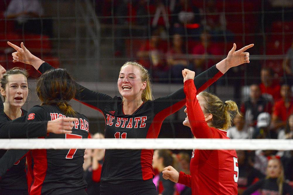 Junior outside hitter Julia Brown raises both hands into the air and cheers after the Wolfpack team won a point against Syracuse at Reynolds Coliseum Oct. 21. Brown achieved five spikes, 31 kills and two blocks. The Wolfpack won the game against Syracuse 3-2.