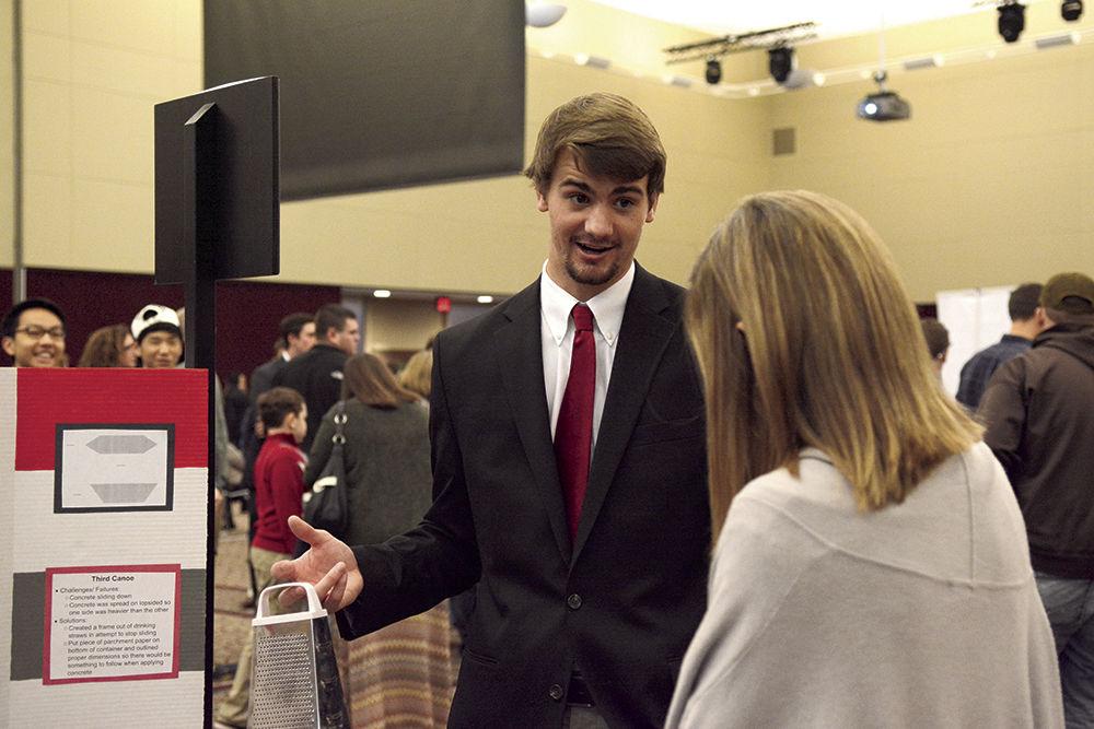 Asa Rogerson, a freshman studying engineering, tells Lori Sneed, whose son is also a first-year engineering student, about the use of a cheese grater in his group's concrete canoe design project. Rogerson explained that many of the materials his group used to make the canoes were household kitchen items, and the canoes performed successfully at Freshman Engineering Design Day in the McKimmon Center on Nov. 22.