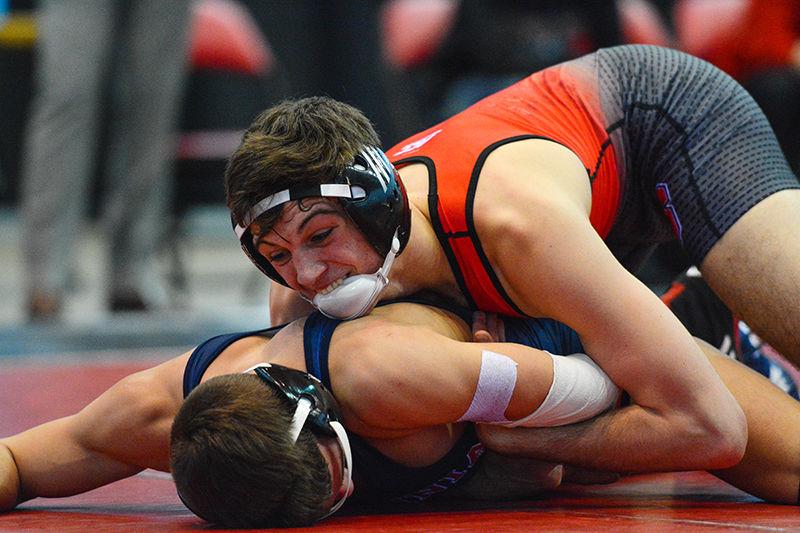 Redshirt freshman Sean Fausz bites his chinstrap and holds his opponent tight in the Wolfpack's meet against No. 17 Virginia on Jan. 17. The 125-pound Fausz won his bout 8-4 and helped the Wolfpack to a 35-7 win over Virginia at Dorton Arena.