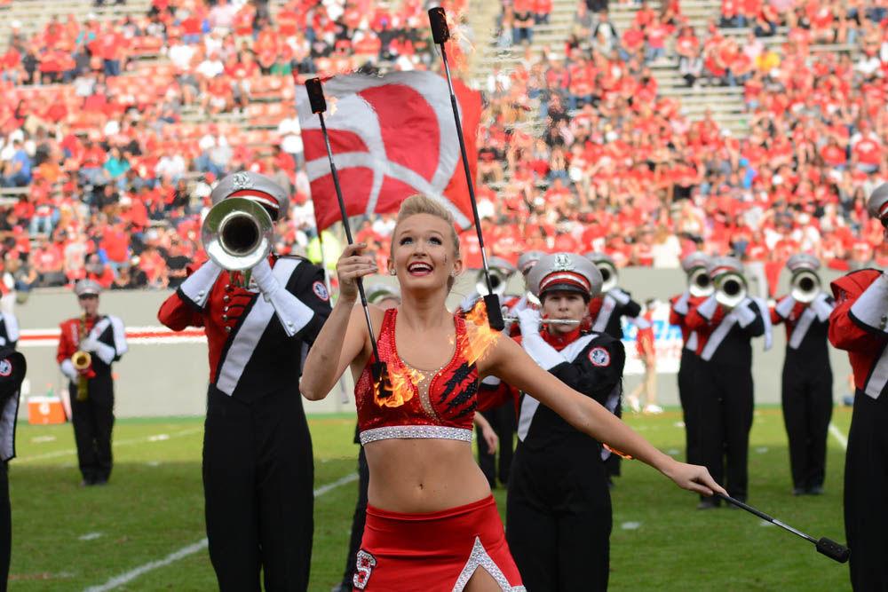 Valerie Stevens, a sophomore studying middle grades education, twirls fiery batons as part of the halftime performance duing the football game at Carter-Finley Stadium on Saturday. The halftime show feaured songs from Pixar's The Incredibles. The Wolfpack was defeated by Miami 27-13.