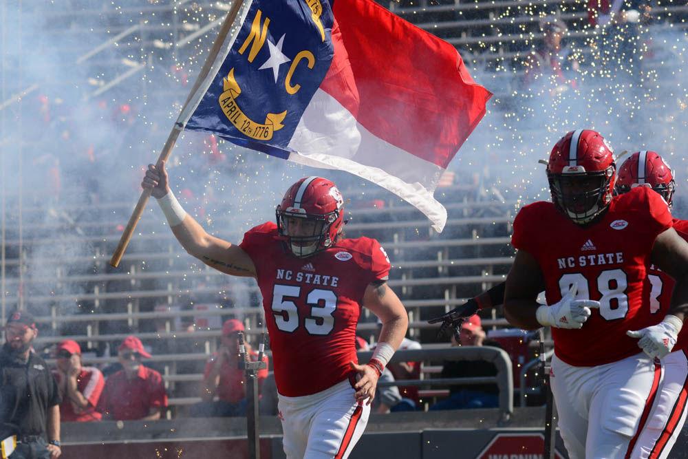 Freshman linebacker David Pierson carries the North Carolina flag on the field at the start of the Saturday game at Carter-Finley Stadium against Miami. The final score was 13-27 in favor of Miami.