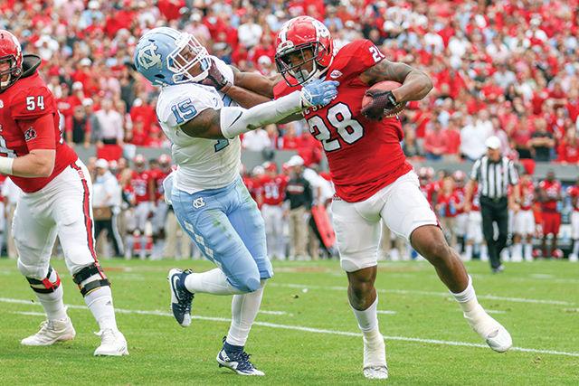 Sophomore tight end Jaylen Samuels stiff arms a UNC defender in the first half. Samuels finished with three carries for 6 yards and 6 receptions for 97 yards. The NC State Wolfpack fell to the UNC Tar Heels, in the last home game of the season, 45-34 at Carter-Finley Stadium on November 28, 2015.