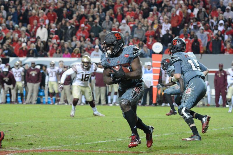 Senior running back Matt Dayes secures the ball before continuing up field. Dayes rushed for a total of 104 yards during the football game against the Seminoles at Carter-Finley Stadium. The Wolfpack were defeated by the Seminoles with a score of 20-24 on Saturday.