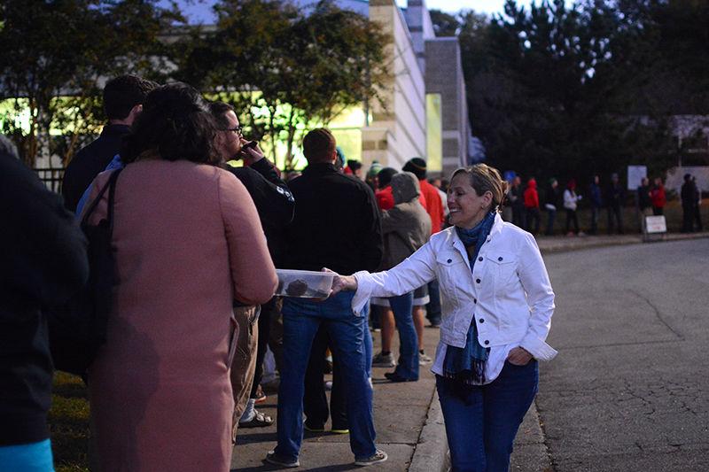 Mary Linda McBride, a volunteer with the Democratic Party, offers cookies to voters standing in line at the Pullen Community Center early Tuesday morning. McBride periodically moved through the line with refreshments and voter guides for citizens to help make the wait a bit more pleasant in the chilly morning weather and to inform people about the candidates on the ballot.