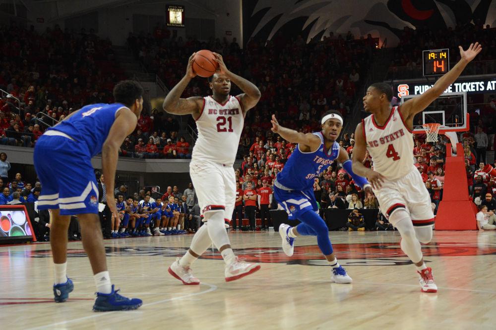 Senior forward, BeeJay Anya passes the ball to Freshman guard, Dennis Smith Jr., while being guarded by a Tennessee State player. Anya rebounded the ball 14 times throughout the game against Tennessee State University. The Wolfpack won the game on Saturday, December 10, 2016, at Reynolds Coliseum with a score of 67-55.