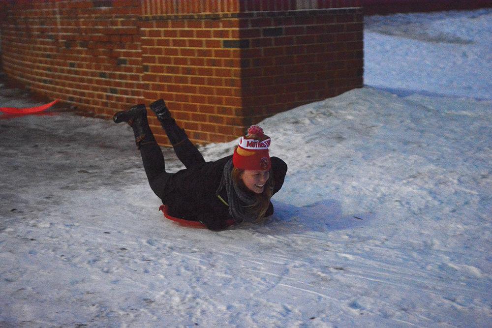 Memoree Blackmon, a senior studying food science, sleds across the sidewalk in the Court of North Carolina on Saturday. A winter snowstorm hit campus late Friday night and students took advantage of the snow and ice to sled, many coming to the hills in the Court of North Carolina. Some students, including Blackmon, had store-bought sleds, while others used cardboard boxes, plastic bins and laundry baskets to slide down the slopes.