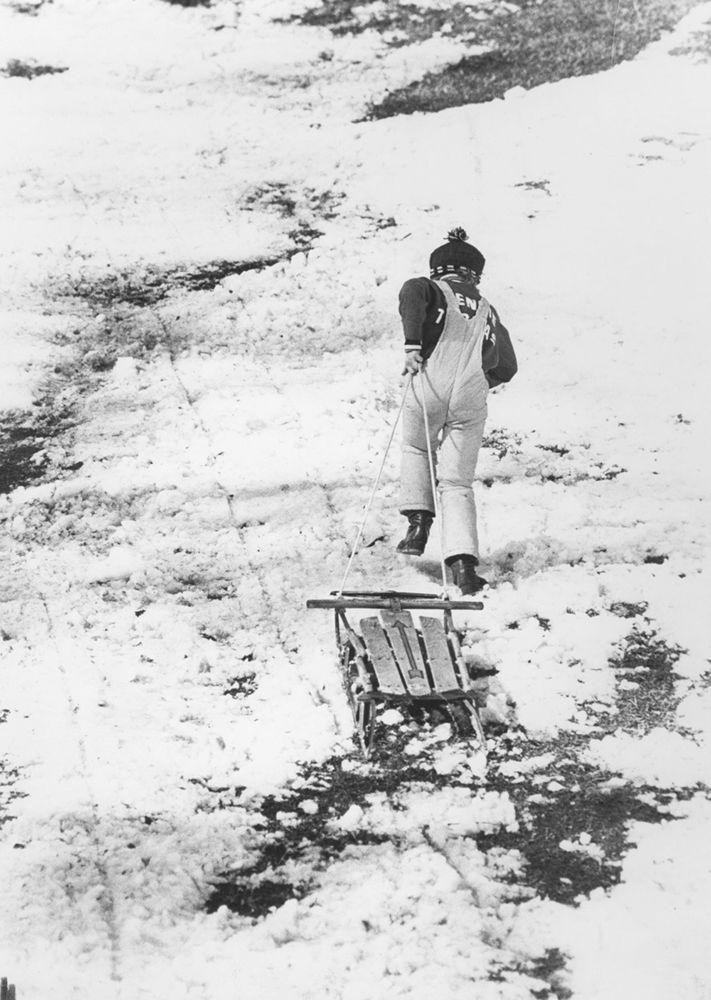 A student drags his sled up a hill, circa 1977.