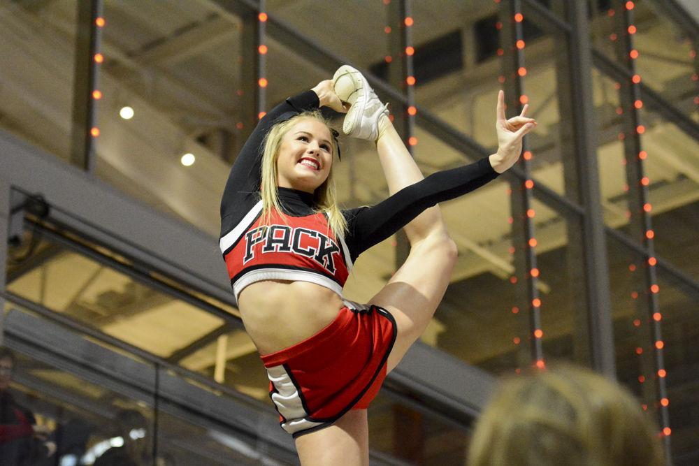 Freshman flyer Delaney Gage forms the Wolfpack sign while being in the air and holding her leg in the quad meet against UNC-Chapel Hill, William &amp; Mary, and Pittsburgh at Reynolds Coliseum on Feb. 10. The meet ended with Wolfpack coming in second, with a score of 195.025, behind UNC-Chapel Hill, 195.625 and ahead of Pittsburgh with 194.075 points.