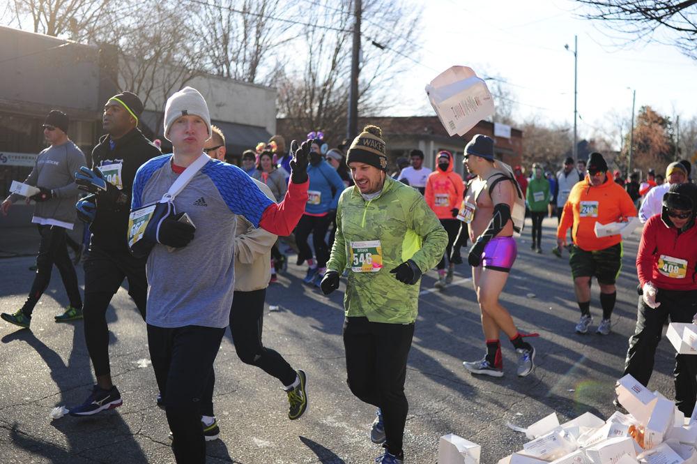 Austin Hollingshead from Baltimore, MD throws away his box of doughnuts at the Krispy Kreme Challenge as he passes the halfway point. The Krispy Kreme Challenge raises funds for the North Carolina Children's Hospital.