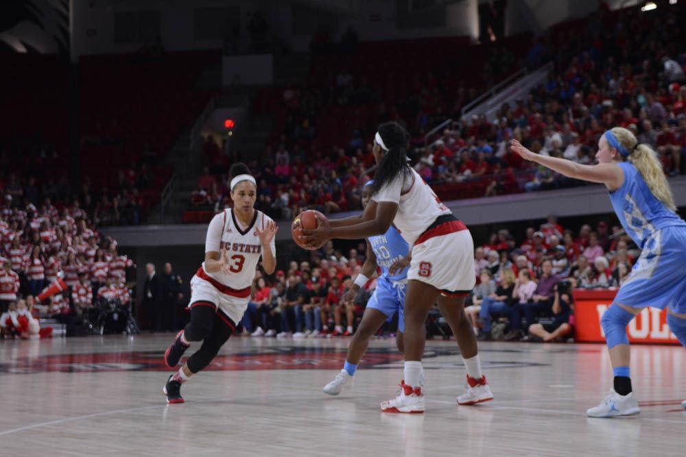 Senior forward Jennifer Mathurin passes the ball to senior guard, Miah Spencer, during the game against the UNC-Chapel Hill. Mathurin scored a total of 13 points throughout the game in Reynolds Coliseum. The Wolfpack were triumphant over the Tar Heels with a score of 80-60 on Thursday, Feb. 23.