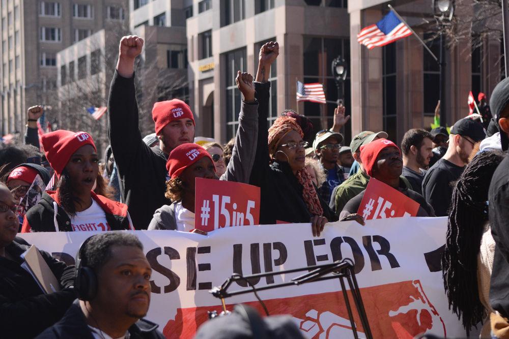 Protesters raise their fists together in front of the Capitol during the 11th Annual Moral March in downtown Raleigh on Sat. Feb. 11, 2017. Some wore hats that said, "Raise Up." They are part of the coalition, Raging Wages NC.