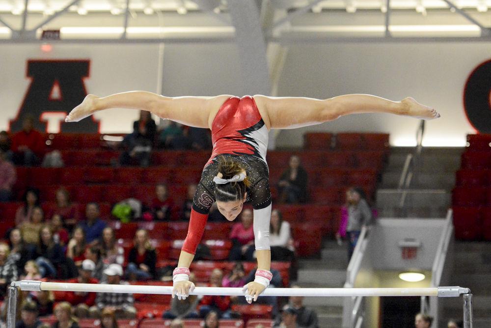 Senior gymnast Amanda Fillard balances on top of the uneven bars with a split in Reynolds Coliseum on Feb. 10. In the quad meet with William &amp; Mary, Pittsburgh, and UNC-Chapel Hill, Fillard finished second in the uneven bars with a score of 9.875. The meet ended with Wolfpack coming in second, with the score 195.025, behind UNC-Chapel Hill with a score of 195.625 and ahead of Pittsburgh who scored 194.075 points, and William &amp; Mary who scored 193.025 points.