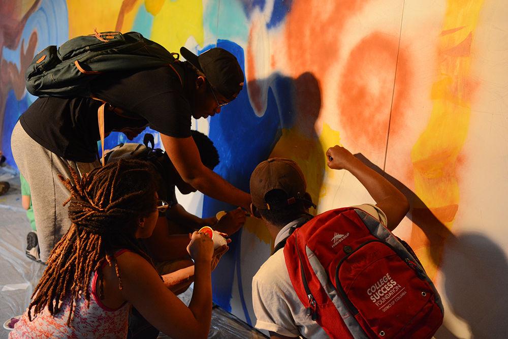 Christopher Jordan, a sophomore studying business administration, Travon Putman, a freshman studying math, and Rephael Scott, a freshman studying theater, help to paint a mural by NC State alumna Dare Coulter at NileFEST on Stafford Commons on Tuesday. NileFEST is the culmination of the Nile Project's residency at NC State LIVE, featuring a concert by The Nile Project, an interactive mural, and food from the Nile region. Coulter's art has been featured in "Black on Black", a show at the Visual Art Exchange in downtown Raleigh.&#160;