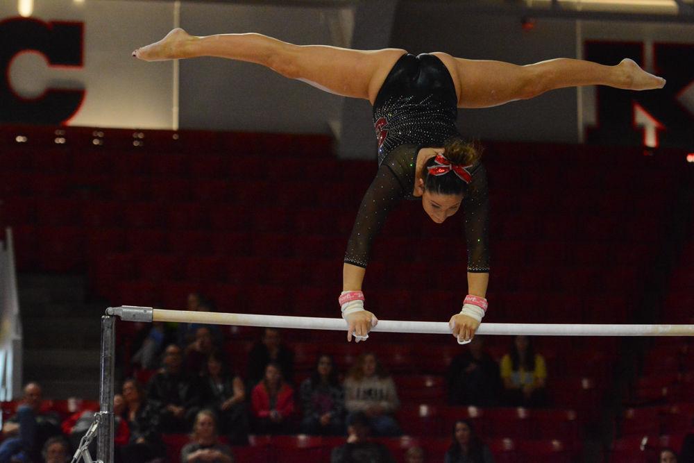 Sophmore gymnast Caitlyn Fillard did a split while balancing on one of the uneven bars at the Reynolds Coliseum on March 18, 2017. Fillard receives 9.75 in the vault event, 9.775 in the bars event, and 9.025 in the beam event. NC State won 3rd place with the score of 194.875 in the meet with George Washington University, University of New Hampshire, UNC Chapel Hill, University of Pittsburgh, and Towson University.