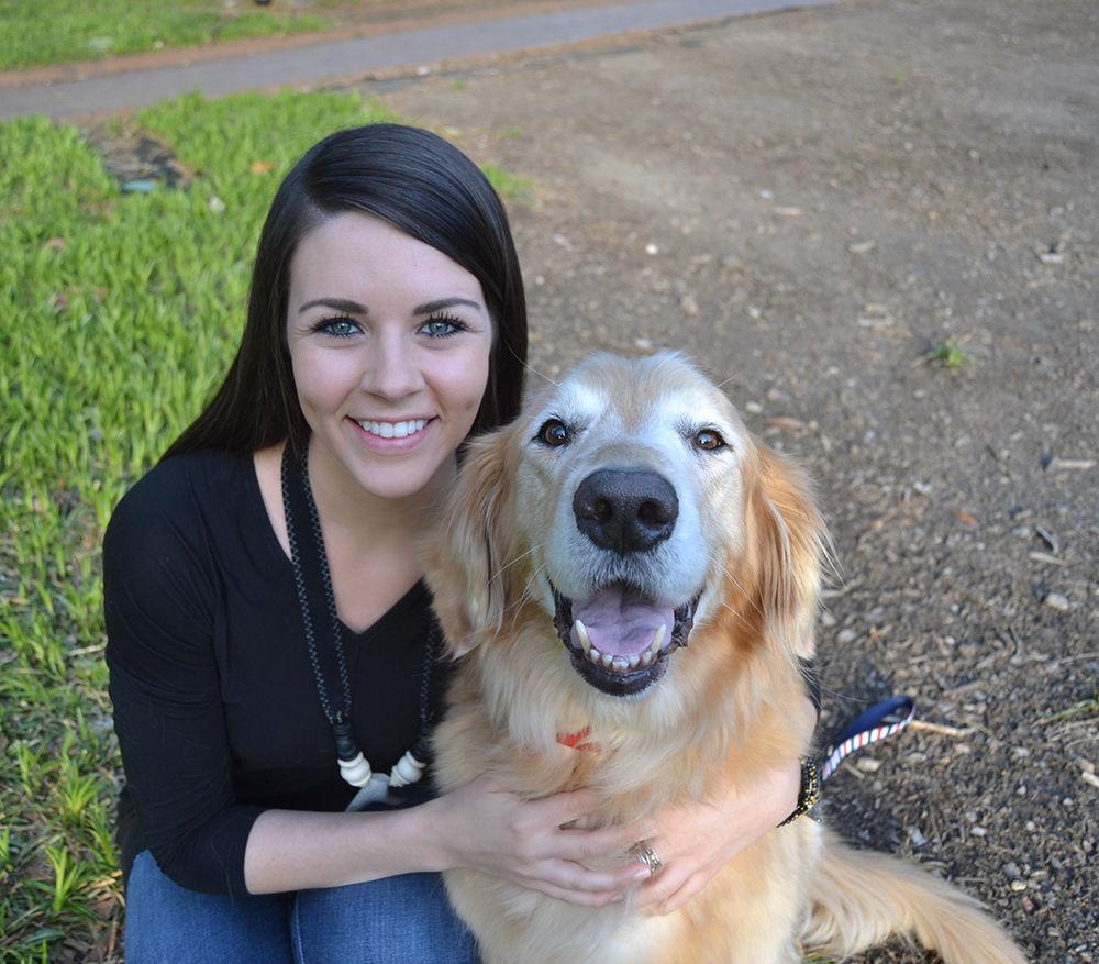NC State graduate Catherine Guy kneels beside her therapy dog, Duke, in the Court of North Carolina on Monday. "My reason for starting Retrieving Hearts was to combine my two passions together: people and animals," Guy said.
