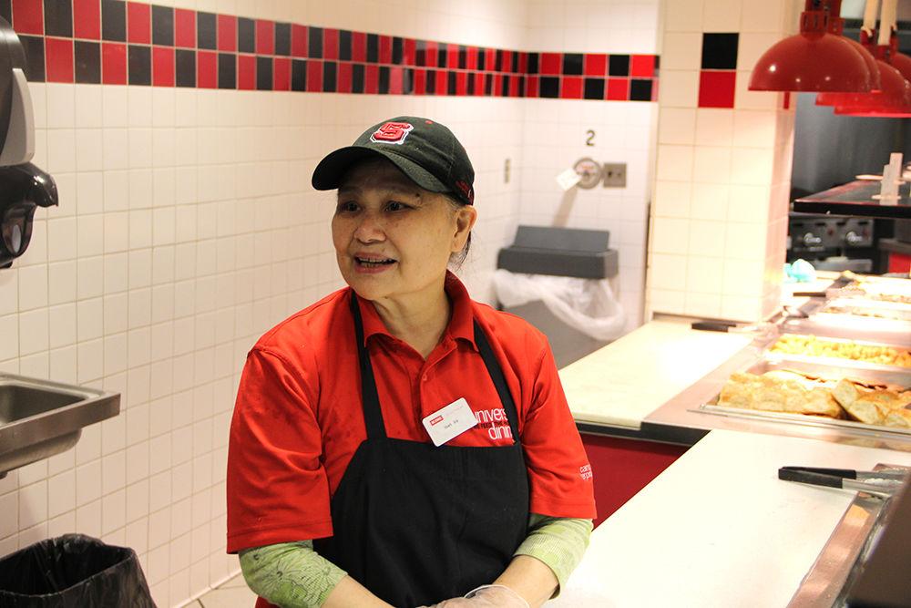 Loan Thi Vo, 64, smiles as a coworker speaks to her after placing a fresh tray of fruit out for students during breakfast. She immigrated to the United States from Vietnam.