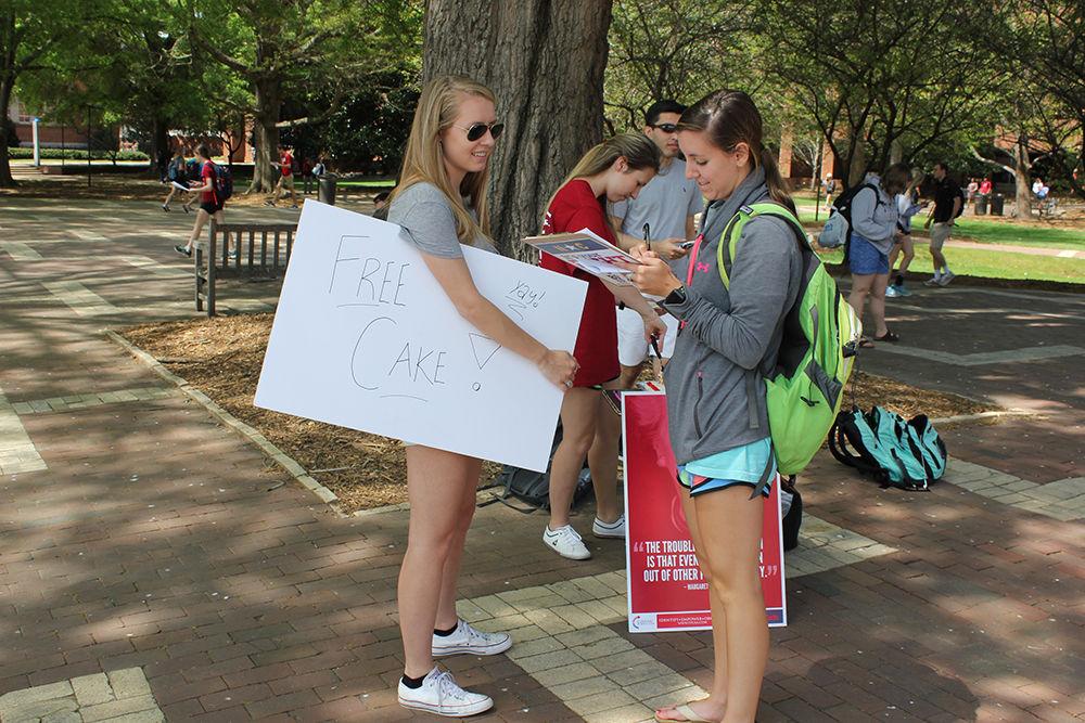 Students from the organization Turning Point USA hand out cake slices to show how much each individual would have to pay in order to pay off America&#8217;s national debt on Wednesday. Turning Point USA is a nonprofit that helps to educate students about limited government, free markets and fiscal responsibility. Its focus is on economic issues and limited government.&#160;
