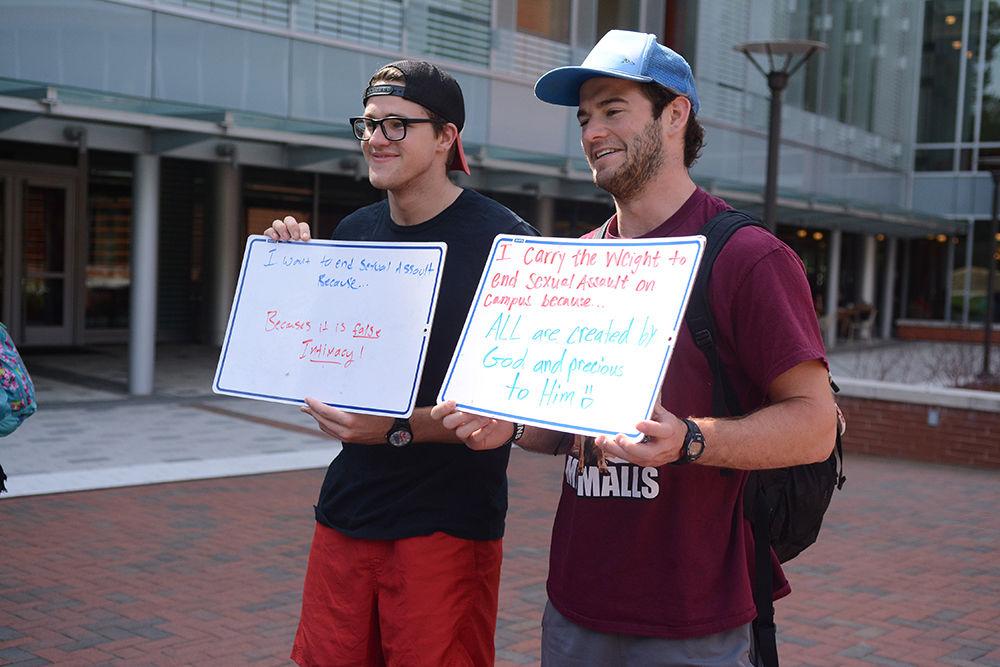 Austin Clark, a senior studying communication and Chris Kabrich, an alumnus studying civil engineering, pose for pictures while holding up signs explaining their reasons for wanting to end sexual assault on campus by Talley Student Union Wednesday, Apr. 12, 2017. Kat Kirby, Intern with the Women's Center and sophomore studying women &amp; gender studies and Maggie Schroder, a junior studying social work and Spanish and President of the Movement Peer Educators, gave students the opportunity to explain why they feel it's important to end sexual assault on campus and to support survivors as part of an event titled "Carry That Weight" which was part of Sexual Assault Awareness Month.