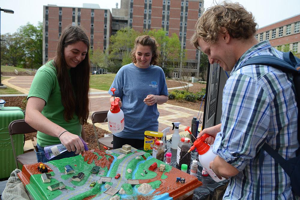 Katie Lokey, a junior studying environmental technology and management, Lauren Vess, a senior studying environmental technology, and Matt Moore, a senior studying natural resources management, spray a watershed model during the annual NC State Earth Fair at the Brickyard Wednesday. The demonstration, hosted by representatives from the NC State Environmental Health and Safety Center, showed how most storm water flows to the creek rather than to the wastewater treatment plant. "It's been really great seeing all the groups out here," Moore said. The Earth Fair offered students and the public the opportunity to learn about sustainable options and making the world a better place.