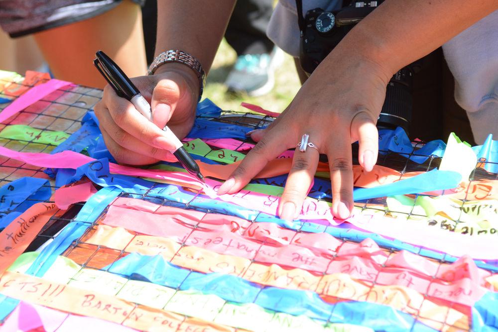 A visitor to the community science fair held in Moore Square writes a message on a plastic tape scrap to be weaved into a giant mat, a community weaving project, which was one of many stations set up to educate citizens about the importance of science. The community science fair was part of the first ever Raleigh March for Science held on Earth Day, April 22, 2017.