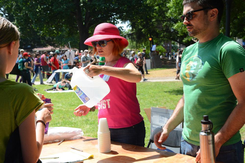 Hollianna Bryan pours water for a Raleigh March of Science participant at the welcoming table in Moore Square on April 22, 2017. Bryan and Kevin Tellford manned the table which served to welcome people to the community science fair held in Moore Square and inform them of the fair and rally being held, as well as supply attendees with a drink of water.