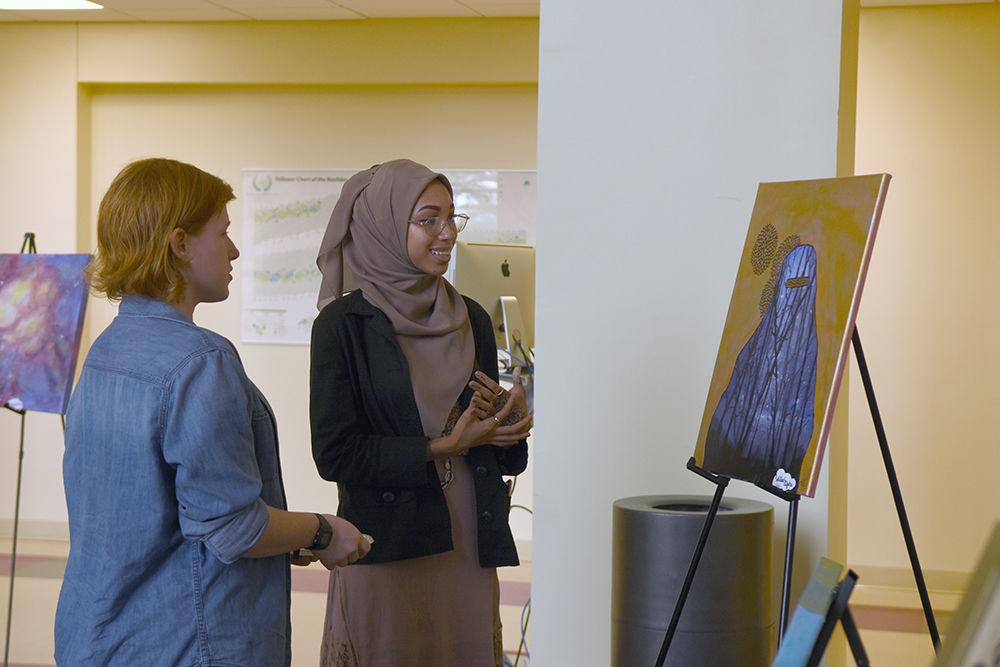 Chelsea Senter, a senior studying nutrition, discusses "Veiled Night" with the artist, Sumaiyah Jones on Wednesday in Riddick Hearth for the MSA Art Expo. Jones, a Wake Tech student said that the theme of "Veiled Night" was "to show that a woman can still be feminine while covering her body completely."