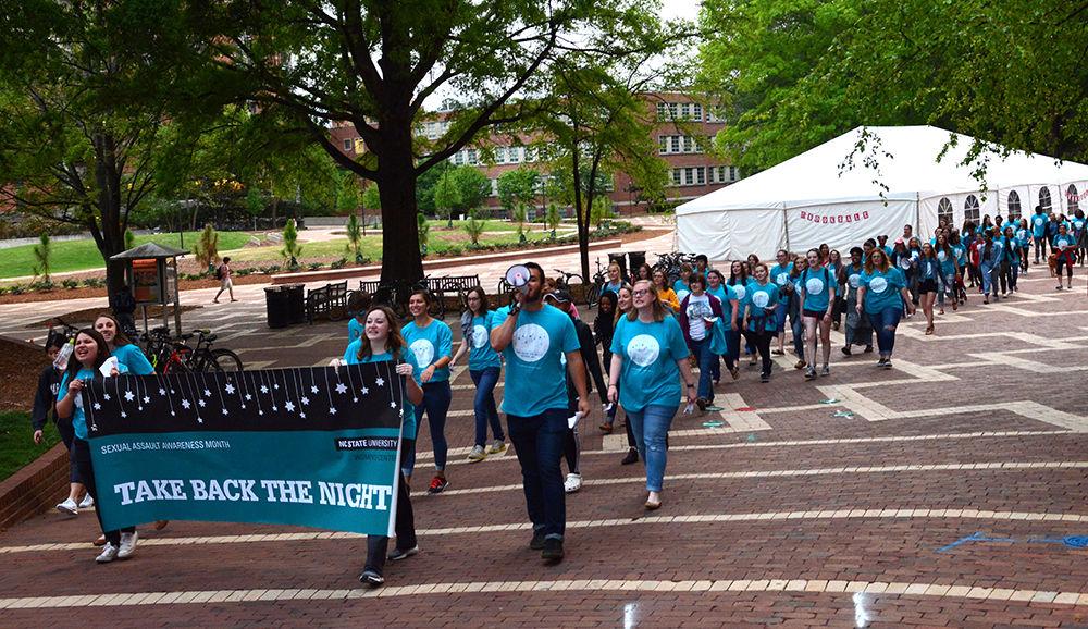 Students march through the Brickyard as a part of the Take Back the Night event on Wednesday. The event was started to help put a stop to rape culture and to address issues of sexual violence on campus.