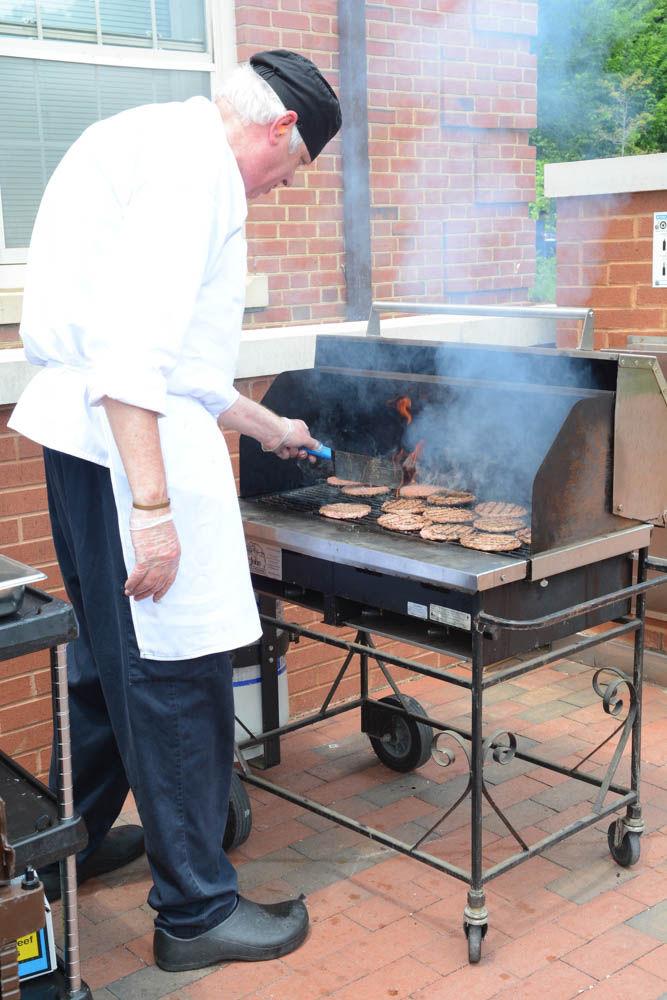 Thomas Imboden, an employee from the catering kitchen located in Talley Student Union, flips burger patties outside of Alexander Hall on April 28, the last day of spring semester classes. The burgers were served in an outdoor buffet on Stafford Commons. In addition to the buffet, students could have picked up a voucher for free food from local food truck businesses or played one of many games located at Wolf Plaza and Stafford Commons.