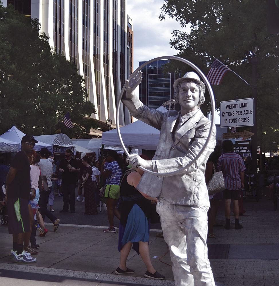 People stop to watch a street performer at Artsplosure on Fayetteville St. in downtown Raleigh on Saturday, May 20, 2017. The performer twirled a hula hoop with stiff motions, acting like a live sculpture.